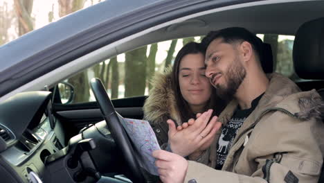 pareja caucásica enamorada abrazándose y besándose dentro de un auto en un bosque nevado.