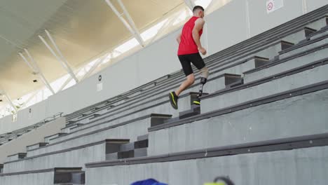 caucasian disabled male athlete with prosthetic leg training, running up stairs