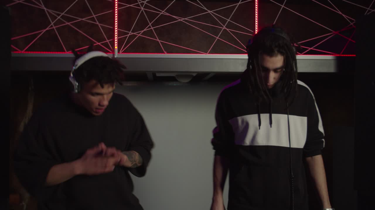 나이트클럽에서 라이브 공연을 하는 동안 현대적인 인사 몸짓을 하는 활기찬 멋진 다문화 dj