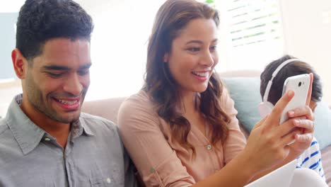 Glückliche-Familie-Mit-Laptop,-Mobiltelefon-Und-Digitalem-Tablet-Im-Wohnzimmer