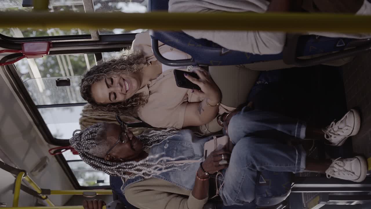 Two diverse women using smartphones on a bus