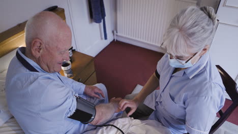 nurse taking blood pressure of elderly patient