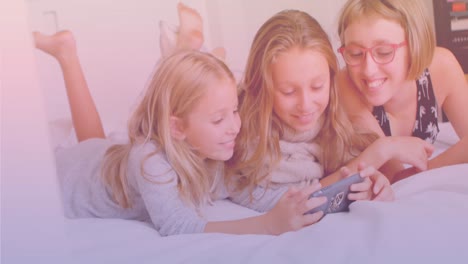 three caucasian sisters using smartphone together while lying on the bed