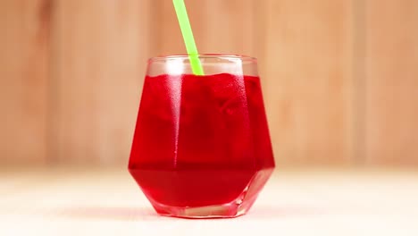 hand stirring red drink with green straw