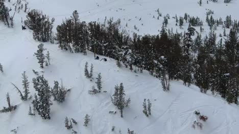 awesome cinematic 4k aerial footage of a group of skiers waiting to bomb down the face of a mountain in the backwoods of lake tahoe, california during winter with a snow storm.
