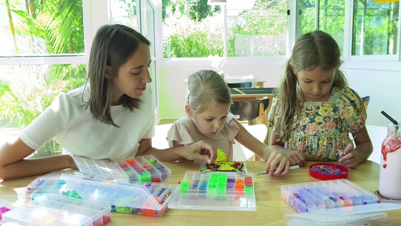 madre e hijas haciendo un mosaico de cuentas coloridas juntas