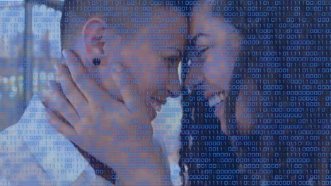 animation of binary code over happy diverse lesbian couple hugging