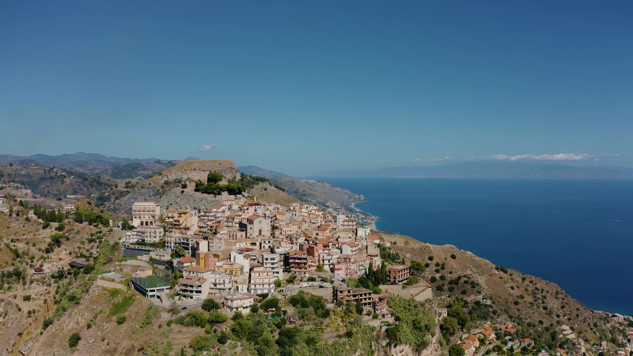 Betagende luftfoto af landsbyen Castelmola højt oppe på en bjergskråning på Sicilien. Historisk by i Italien med udsigt til Middelhavet. Vidstrakt panoramaudsigt til en by i bjergene