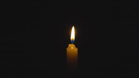 a single white candle burning. looping for use as a background or illustration of remembrance or celebration. the wind tries to put out the flame, but it recovers each time. the eternal flame.