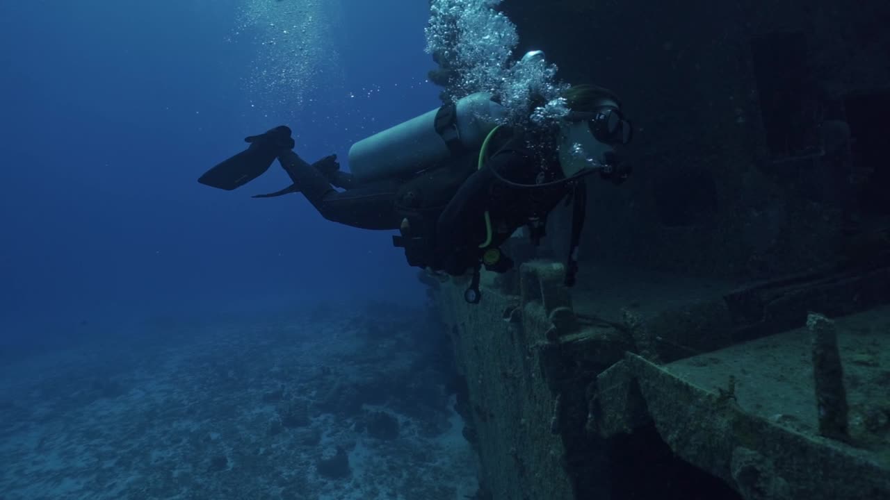 A woman in full scuba gear glides past the massive hull of the ARM General Felipe Xicoténcatl (C-53), Cozumel's premier artificial reef dive site