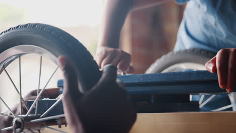 Close-up-of-father-and-son’s-hands-screwing-in-a-bolt-while-making-a-racing-kart-together,-selective-focus