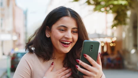 Emocionada-Y-Feliz-Ganadora-Mujer-India-Usa-Un-Teléfono-Inteligente-Celebrando-Ganar-Buenas-Noticias-En-Las-Calles-De-La-Ciudad