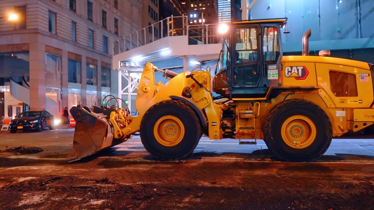 New York, USA, 16 April 2026: Heavy dump truck and wheel loader at night construction site. Industrial dump truck and loader bucket at night roadwork site in New York City.