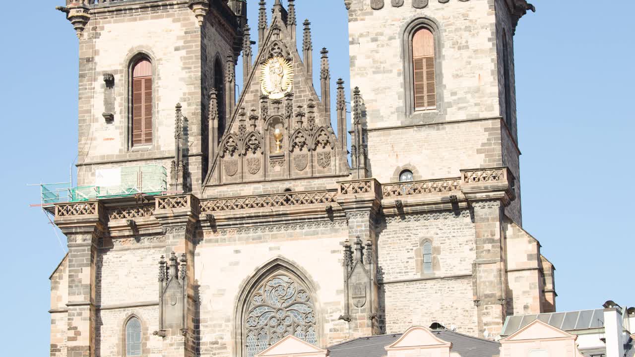 Camera tilts upward on historic stone church towers under clear daylight sky, revealing architectural details
