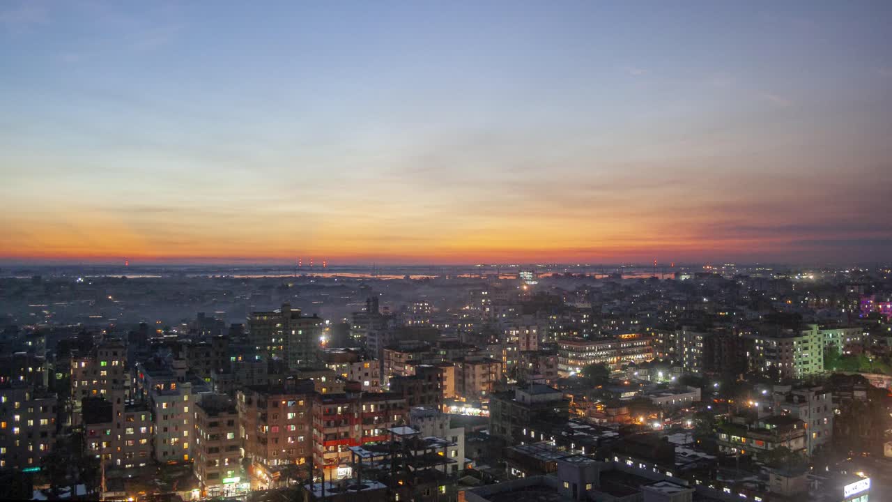 A stunning timelapse of Dhaka's skyline during sunset, capturing the transition from daylight to night as city lights gradually illuminate the buildings.