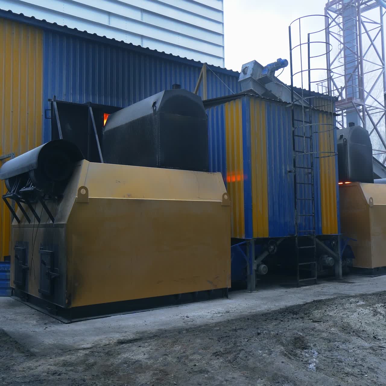Various kinds of premises in the up-to-date agricultural granary storage. The hearth placement exterior with burning charcoal inside. Elevator structures on a foggy day