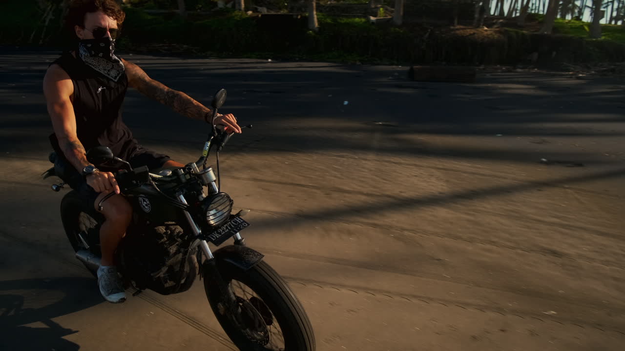 hombre montando una motocicleta en una playa al atardecer