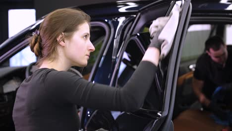 el lavador de coches profesional con guantes negros limpia el coche después de lavar y forrar la cerámica. conceptos de: trabajo profesional, varias herramientas de lavado, limpieza para brillar.