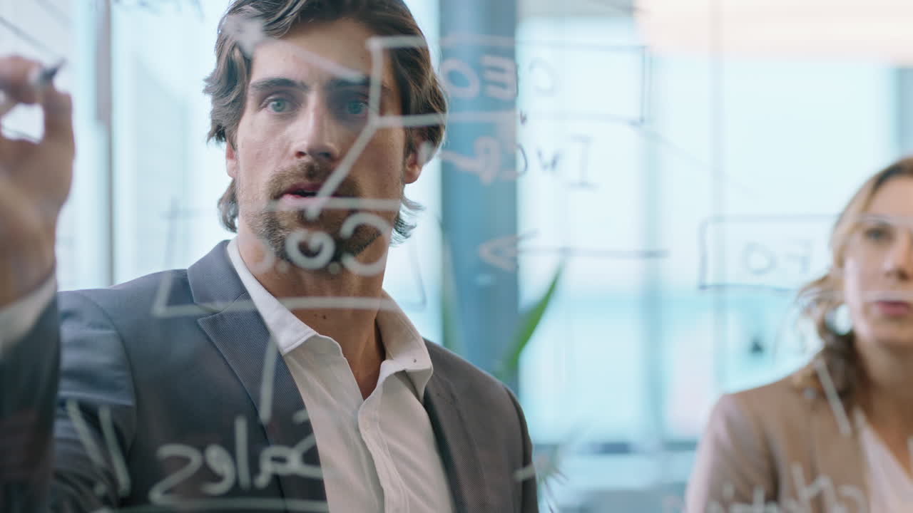 creative business people writing ideas on glass whiteboard team leader man brainstorming with colleagues working on solution discussing strategy teamwork in office meeting through glass 4k