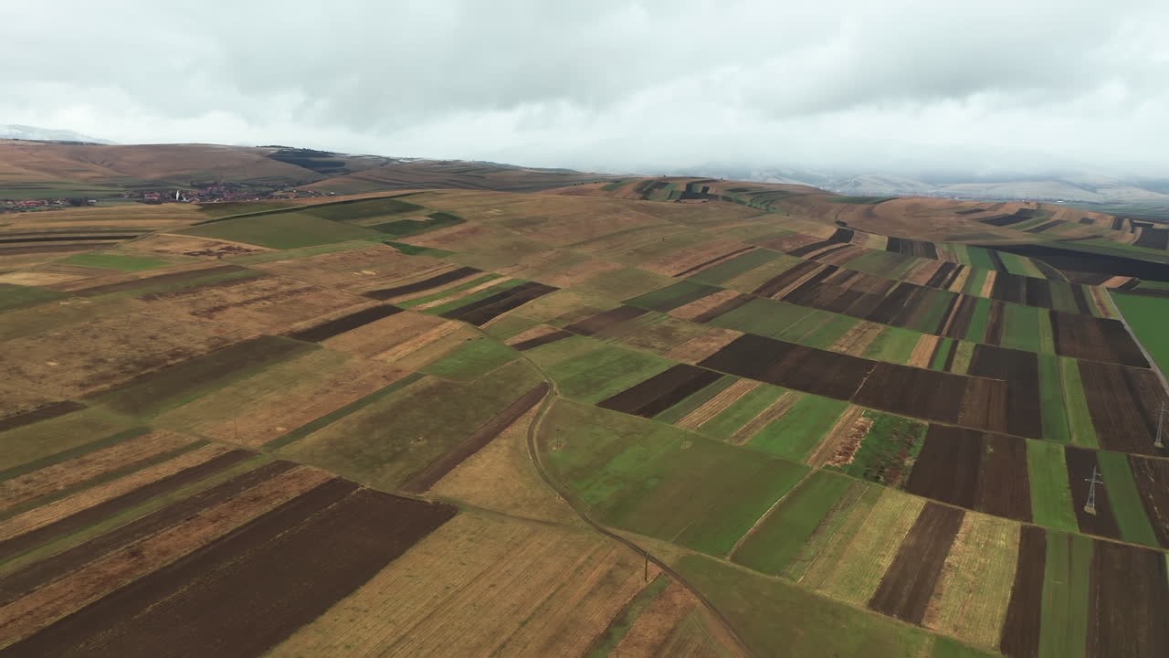 Wide aerial view of cultivated fields in Sancraieni, Romania. Slow dolly forward