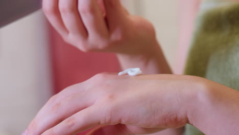 close-up view of woman dripping cream onto her left hand, preparing to moisturize, the focus is on the smooth application of the cream, ensuring hydrated and healthy skin