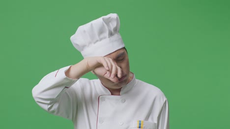 close up of asian man chef wiping the sweat being tired cooking while standing in the green screen background studio