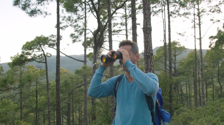 Happy man admiring nature through binoculars