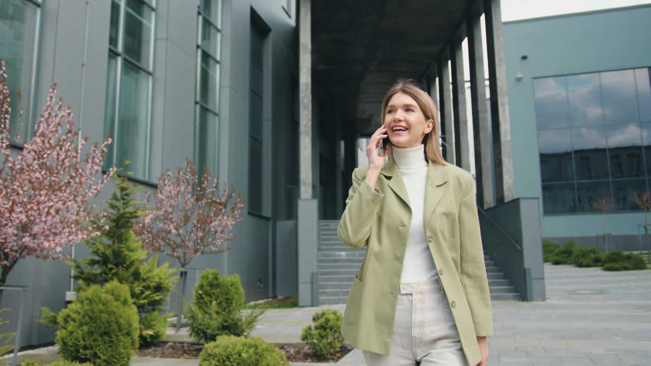 Portrait of happy young Caucasian beautiful female after work, walking in city and speaking on smartphone. Outdoors. Urban concept