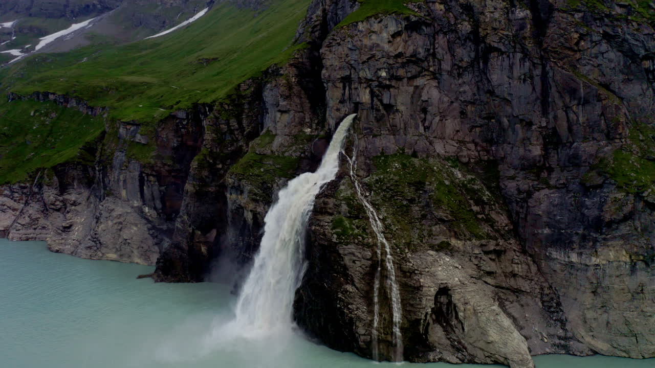 Stunning FPV and drone shots soaring through the Swiss Alps, capturing the Mauvoisin Dam and its majestic waterfall on a clear, sunny summer day.