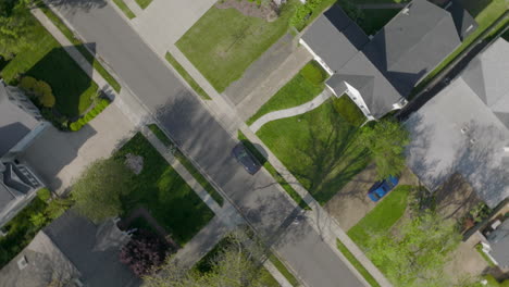 aerial straight down over suburban houses and street with a bike rider on the street as camera spins