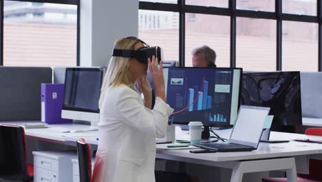 Caucasian-businesswoman-using-vr-headset-at-desk-in-office