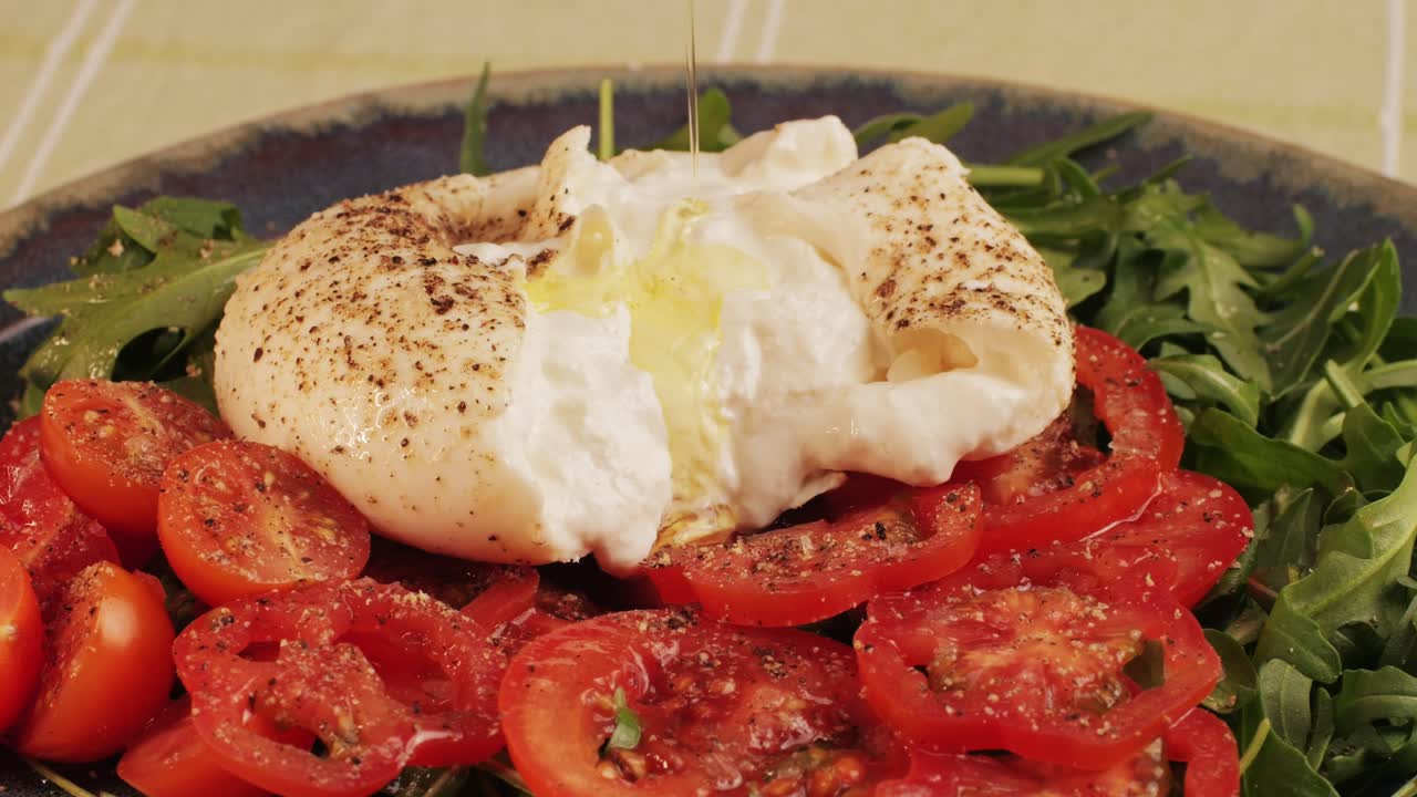 Burrata or Mozzarella cheese on fresh tomatoes and green arugula on plate close-up. From Italian cow's milk cheese made from mozzarella and cream.The outer casing is solid cheese, while the inside contains stracciatella and clotted cream, giving it an unusual, soft texture.