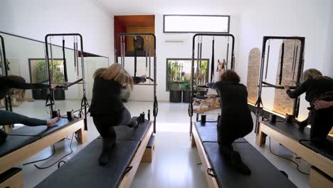 women doing exercises on pilates reformer during training