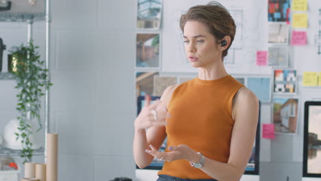 arquitecta femenina de pie en la oficina hablando con el cliente usando auriculares inalámbricos
