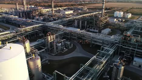 aerial overview of a large industrial complex showcasing extensive pipelines and storage tanks under a clear sky at dusk