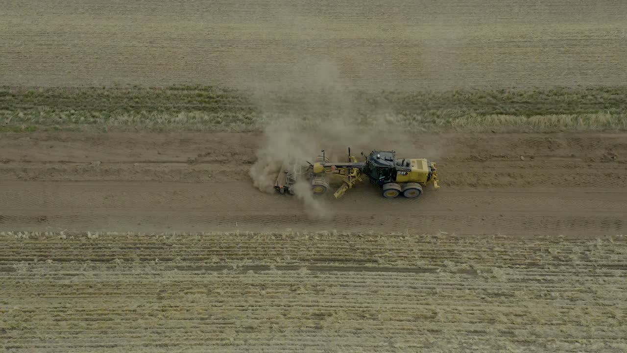 niveladora de carretera maquinaria pesada moviéndose a través de la superficie de nivelación del camino de tierra