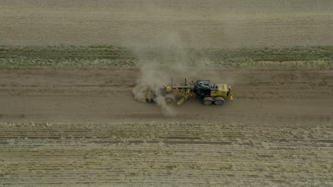 Road-grader-heavy-machinery-moving-through-dirt-path-leveling-surface