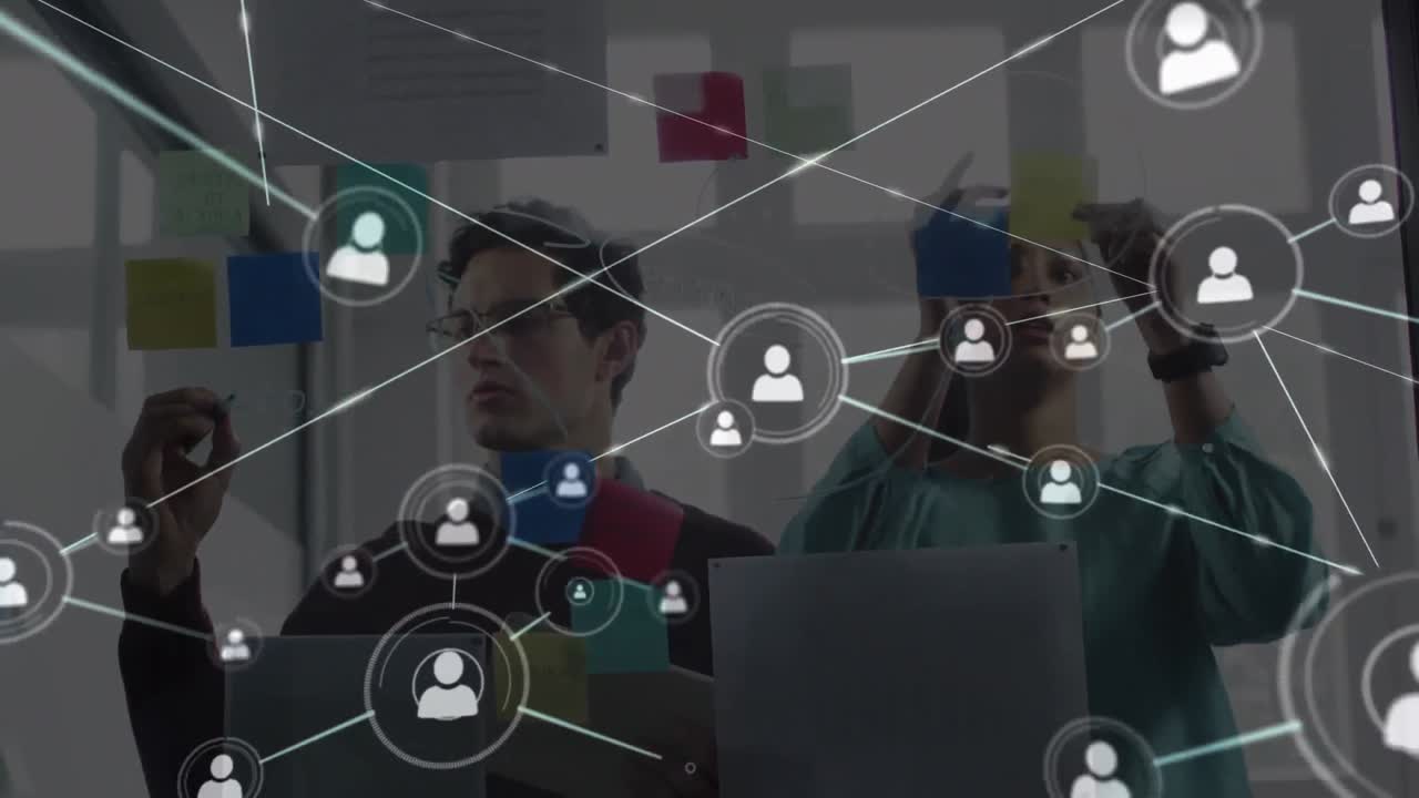 Animation of network of people icons over male and female colleague brainstorming in office