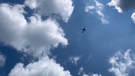 plane is flying in beautiful blue sky with white fluffy clouds. cumulus clouds