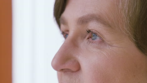 senior woman with gray hair, blue eyes and eyeglasses looking at side