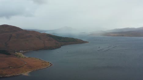 Fish farms in Scotland. Windy day with wind trails in water. Beautiful aerial footage with mountains in the background. Salmon farms.