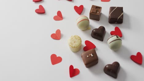 paper hearts and chocolates on pink background at valentine's day