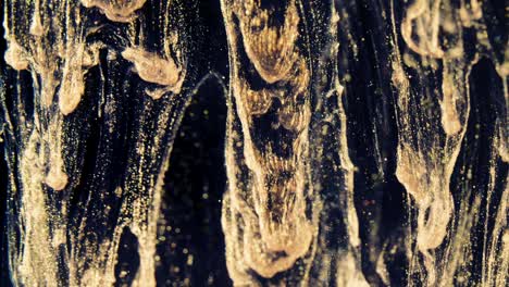 golden ink particles flows in water as colorful chaos on the black background