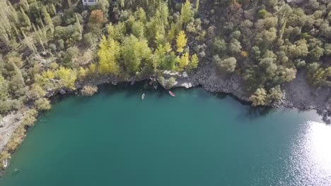 aerial birds eye rising view of boats moored along kachura lake skardu coastline