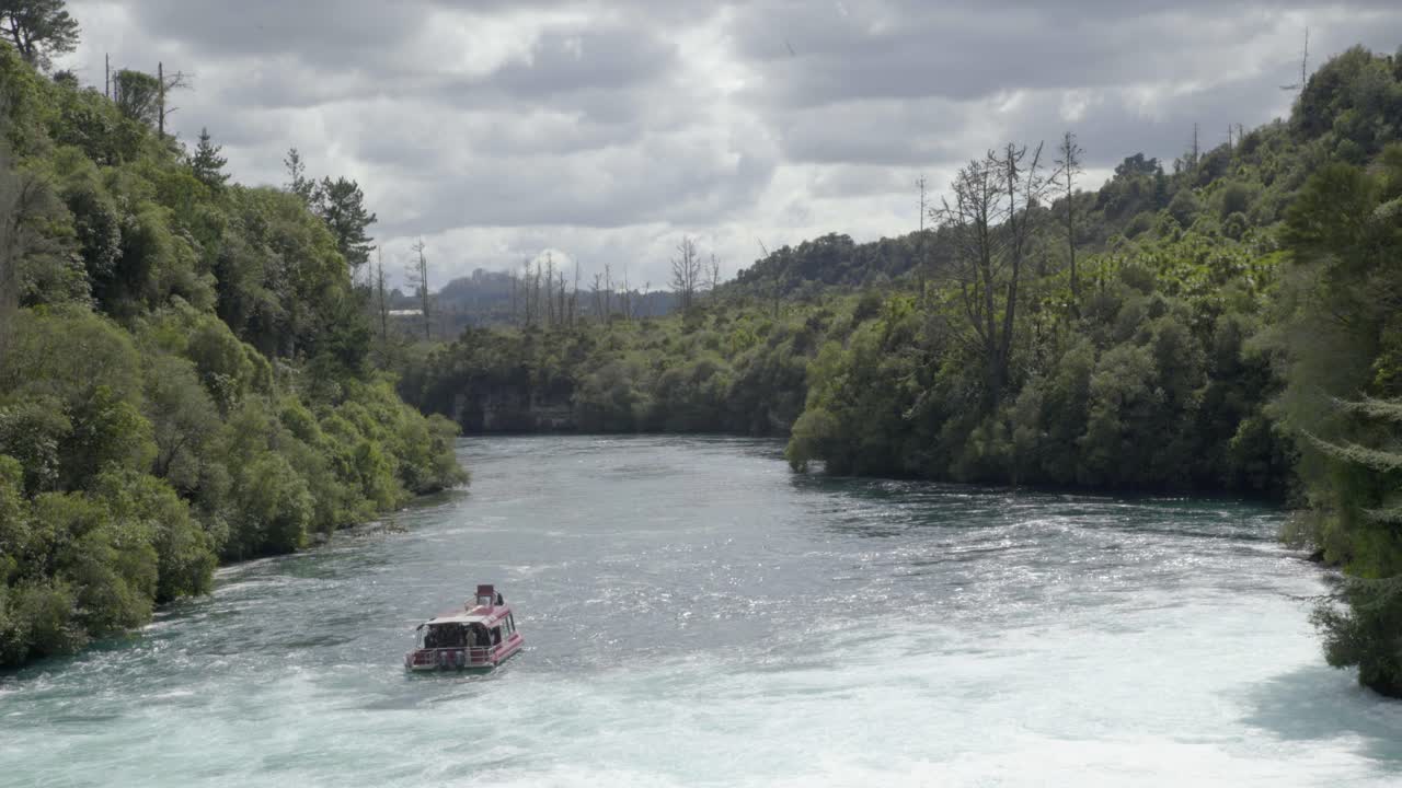 una toma amplia mirando hacia el río waikato mientras el barco de crucero huka falls flota río abajo de las cataratas huka en taupo, nz