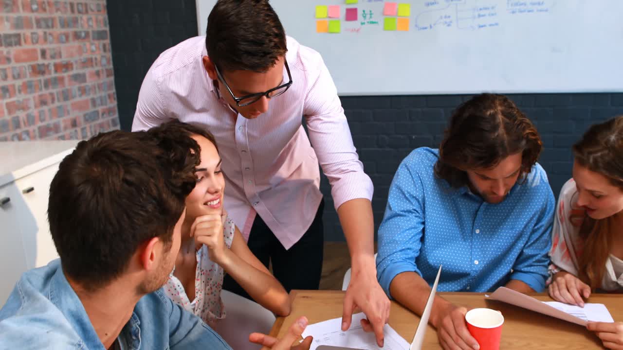 hombre de negocios interactuando con un compañero de trabajo mientras usa una computadora portátil