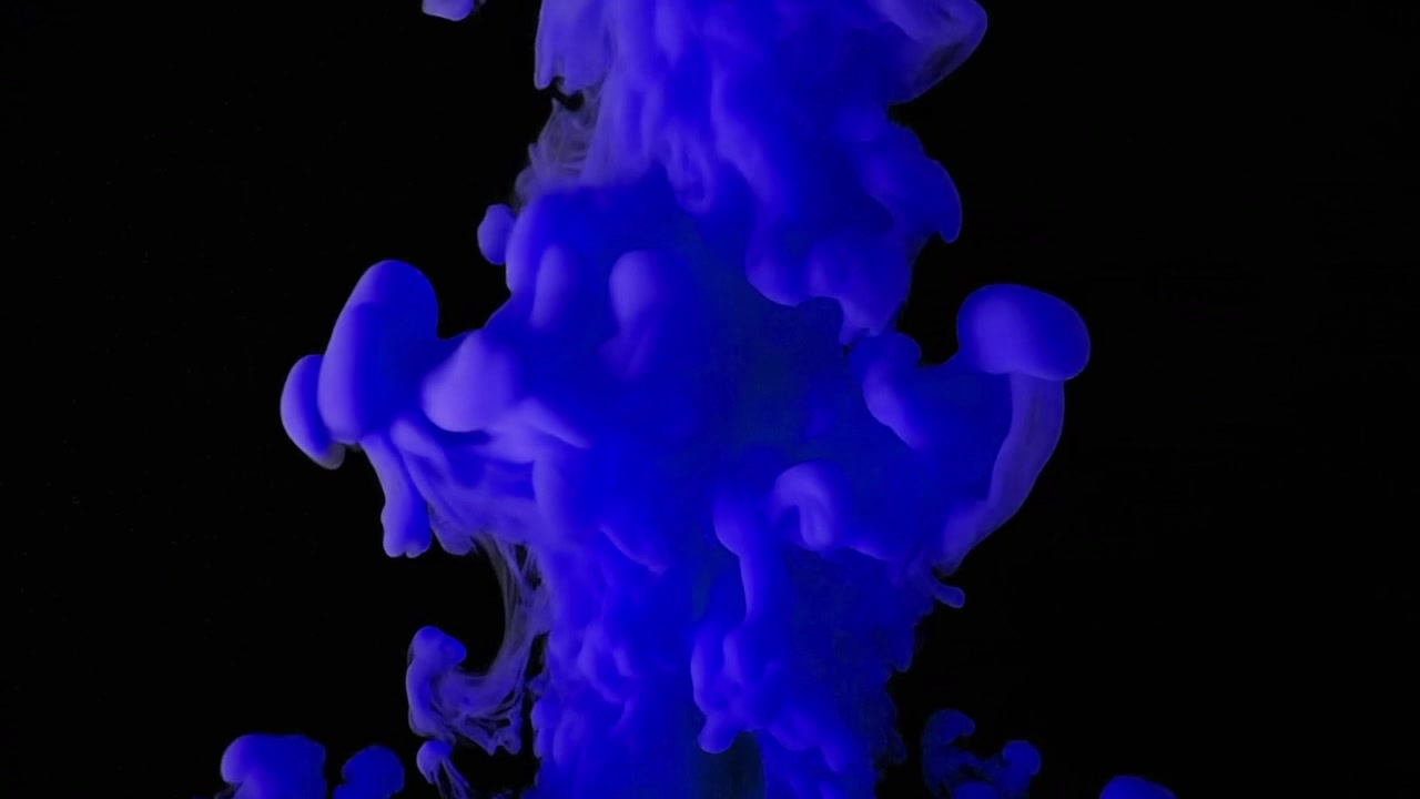 Inchiostro blu che cade e si dissolve nell'acqua su sfondo nero