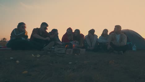 joyful hikers spend time at camping with burning bonfire