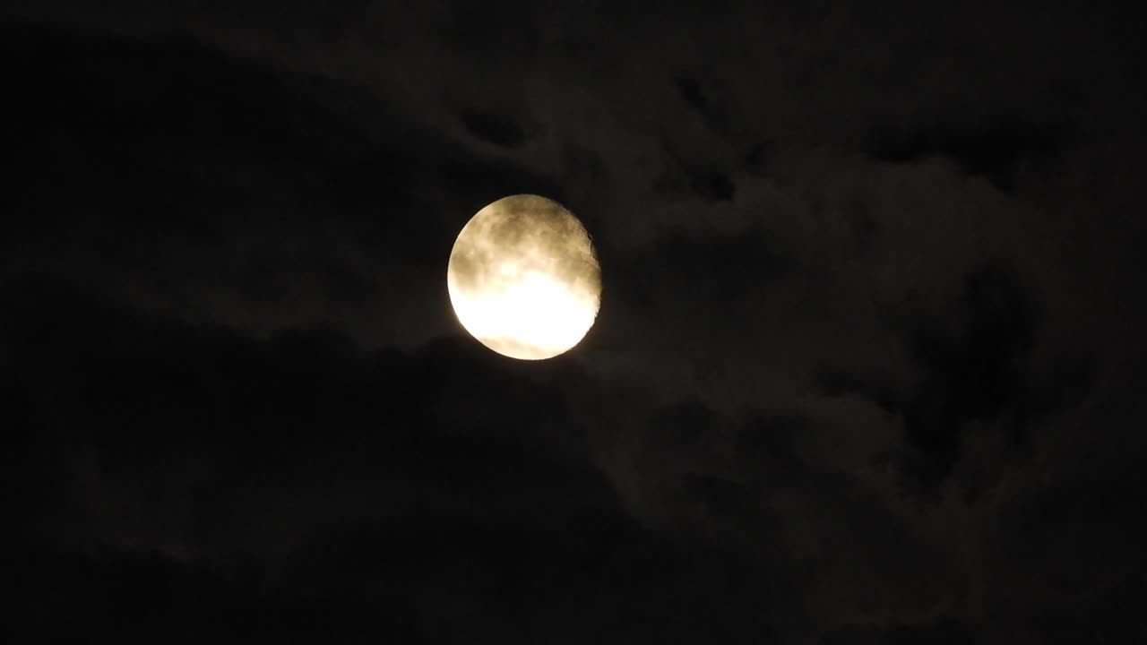 luna por la noche con nubes en tiempo real. 4k video luna en el cielo negro. nubes pasando por la luna por la noite. cielo nocturno con tiempo nublado