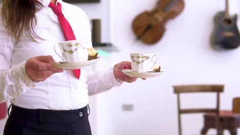 waitress-in-smart-uniform-wearing-black-pants-white-shirt-and-short-red-tie-is-bringing-coffee-to-customers